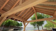 an outdoor covered patio with wooden roof and water in the backgroung area