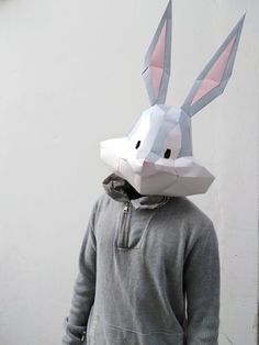 a person wearing a paper bunny mask on top of their head in front of a white wall