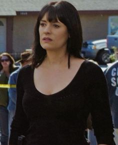 a woman standing in front of a group of people with police tape around her neck