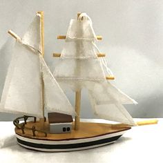 a toy sailboat with white sails on the water