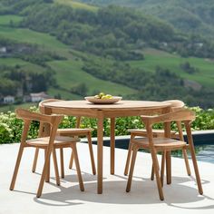 a wooden table with four chairs and a bowl of fruit on top of the table