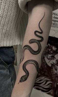 a woman's arm with a snake tattoo on it