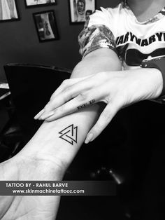 a woman's arm with a small triangle tattoo on her left wrist and the word,