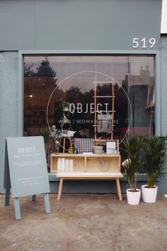 an outside view of a store front with chairs and plants in the window display area