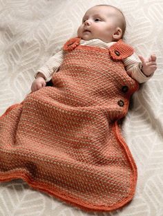 a baby laying on top of a bed covered in a blanket