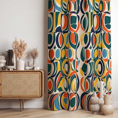 a colorful shower curtain hanging on the side of a white wall next to a wooden cabinet