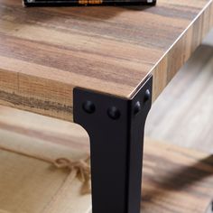 a close up of a wooden table with black metal legs and a book on top