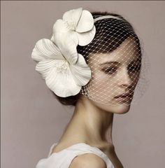 a woman with a veil and flowers in her hair is wearing a white flower headpiece