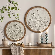 two circular wall hangings above a dresser with vases and other items on it