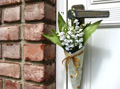 a vase filled with flowers next to a brick wall and a door handle that has a wooden cross on it