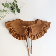 a brown top with ruffles on it and a plant in the back ground