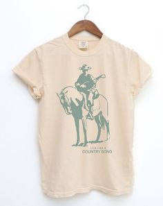 Thanks for checking out this Retro COWBOY T-shirt, This lonely Cowboy with a Guitar on his horse like a Country Song. A classic western Graphic vintage style T-shirt, on an IVORY Comfort Colors 1717 Shirt. Comfort Colors introduces its garment-dyed t-shirt; a fully customizable tee made 100% with ring-spun cotton. The soft-washed, garment-dyed fabric brings extra coziness to your wardrobe while the relaxed fit makes it an excellent daily choice. The double-needle stitching throughout the tee mak Band Merch Cotton T-shirt For Country Concerts, Cotton Band Merch T-shirt For Country Concerts, Retro Cotton T-shirt For Country Concerts, Western Style Cotton T-shirt For Country Concerts, Country Style Relaxed Fit Cotton T-shirt, Graphic Tee T-shirt For Country Festivals, Short Sleeve Graphic Tee For Country Festivals, Country Style Pre-shrunk Cotton T-shirt, Cotton Crew Neck T-shirt For Country Events