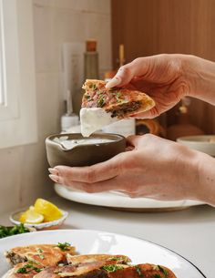 a person is dipping something into a bowl on top of some bread and other food