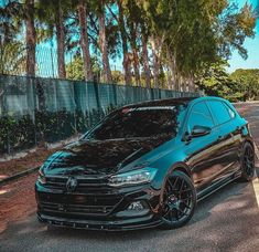 a black car is parked on the side of the road in front of some trees