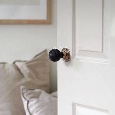 an open door with a black knob on the handle and white pillows in the background