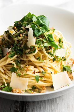 pasta with parmesan cheese and spinach in a white bowl on a wooden table