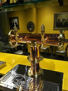 a gold colored water faucet sitting on top of a metal grate next to a yellow counter