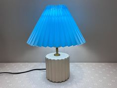 a blue lamp sitting on top of a table next to a white wall and floor