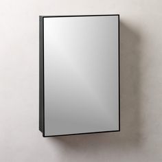 a mirror mounted to the side of a wall next to a white wall with a black frame