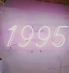 a neon sign that reads'995'in white letters on a pink wall