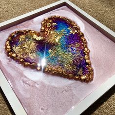 a heart shaped object in a pink box on the floor with gold flecks