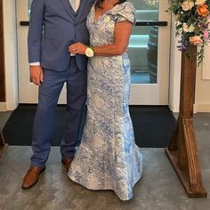 a man and woman standing next to each other in front of a doorway with flowers