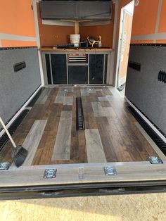 the inside of a camper with wood flooring and storage compartments on each side