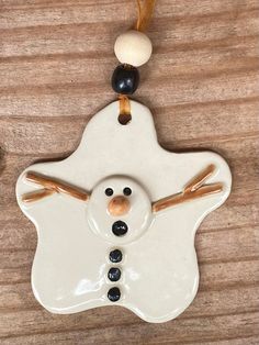 a white ceramic snowman ornament hanging on a wooden table with the caption facebook