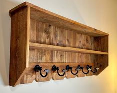 a wooden shelf with five hooks on it