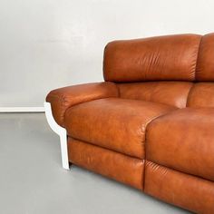 a brown leather couch sitting on top of a white floor