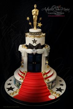 a three tiered cake decorated with an oscar statue and red carpet on the bottom