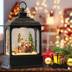 a christmas scene is displayed in a lantern on a table next to other holiday decorations