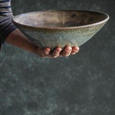 a person holding a large metal bowl in their left hand with both hands on it