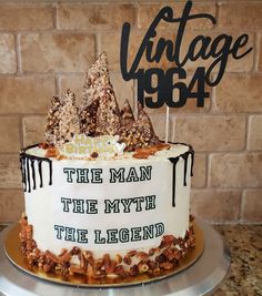 a white cake with black lettering on top and trees in the middle is sitting on a silver platter