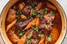 a pot filled with stew and carrots on top of a table