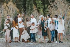 a group of people standing next to each other in front of some trees and bushes