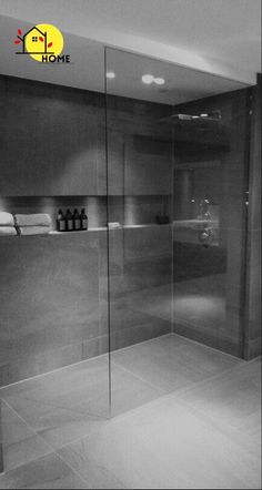 a bathroom with a glass shower door and tile flooring in black and white photo