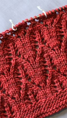 a red crocheted piece of cloth with white thread on the end and two holes in the middle