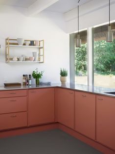 a kitchen with pink cabinets and white walls