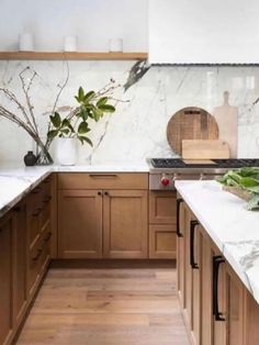 a kitchen with marble counter tops and wooden cabinets, along with potted plants in the center