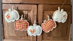 three hearts hanging from clothes pins on a wooden cabinet with gingham checkered fabric