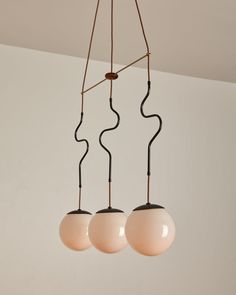 three light fixtures hanging from a ceiling with white walls in the background and two brown lights on each side