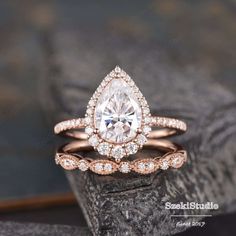 a rose gold engagement ring set with a pear shaped diamond center surrounded by round diamonds