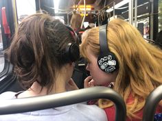 two girls wearing headphones on a bus