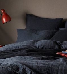 a bed with black linens and a red lamp