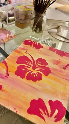 a glass table with flowers painted on it and some brushes in the vase next to it