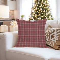 a living room with a christmas tree in the background and plaid pillows on the couch