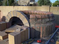 an outdoor brick oven is being built on the side of a building with bricks around it