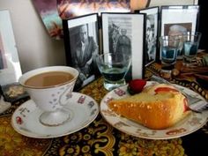 a table topped with pictures and a cup of coffee next to a cake on top of a plate