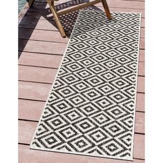 a black and white rug sitting on top of a wooden floor next to a chair